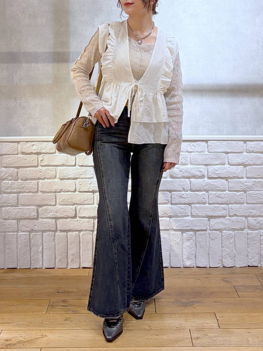 ブルー系のデニムパンツ、ブラウン系のボストンバッグ、ブラウン系のサンダルを着用したレディースの春コーディネートの3枚目の写真