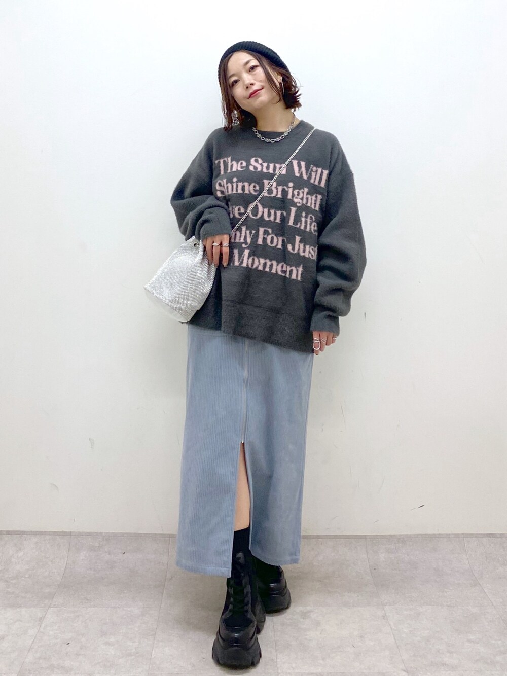 グレー系のニット/セーター、ブルー系のスカート、ブラック系のブーツを着用したレディースの秋コーディネートの9枚目の写真