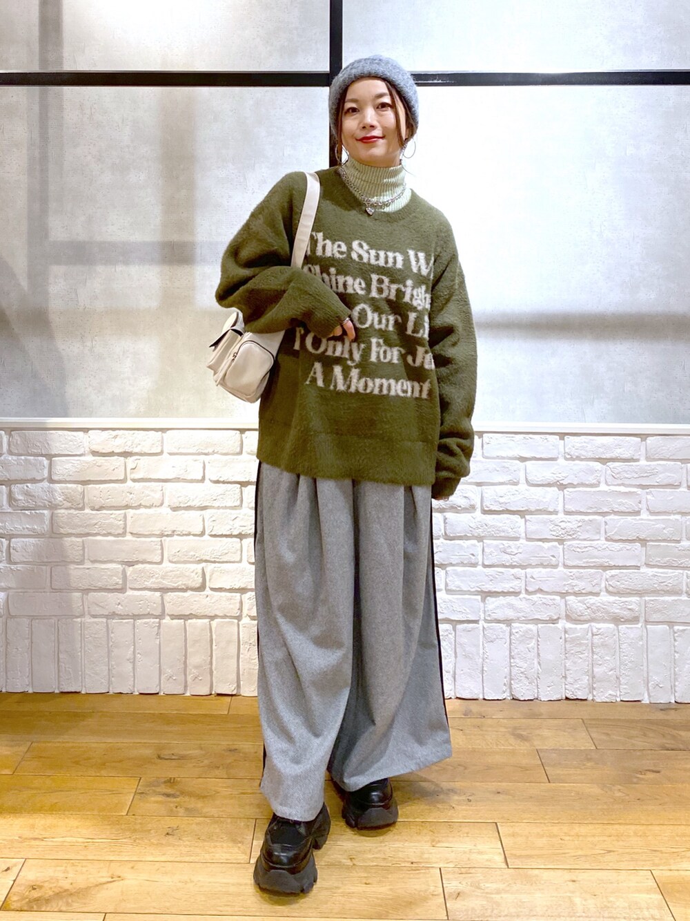 ブラック系のスラックス、グリーン系のTシャツ/カットソー、ブラック系のブーツを着用したレディースの冬コーディネートの4枚目の写真