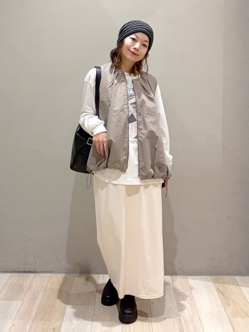 グレー系のベスト、ブラック系のブーツ、ホワイト系のTシャツ/カットソーを着用したレディースの秋コーディネートの9枚目の写真