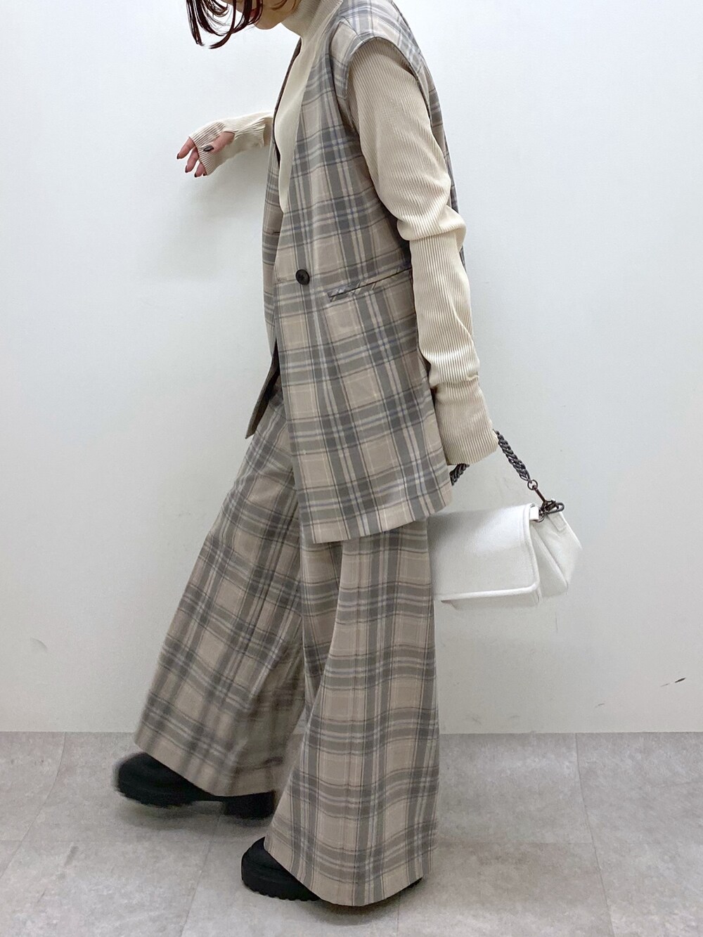 ホワイト系のバッグ、ブラック系のシューズ、グレー系のパンツを着用したレディースの秋コーディネートの5枚目の写真