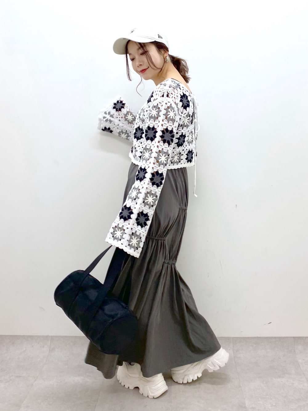 グレー系のスカート、ホワイト系のカーディガン/ボレロ、ブラック系のドラムバッグを着用したレディースの春コーディネートの5枚目の写真