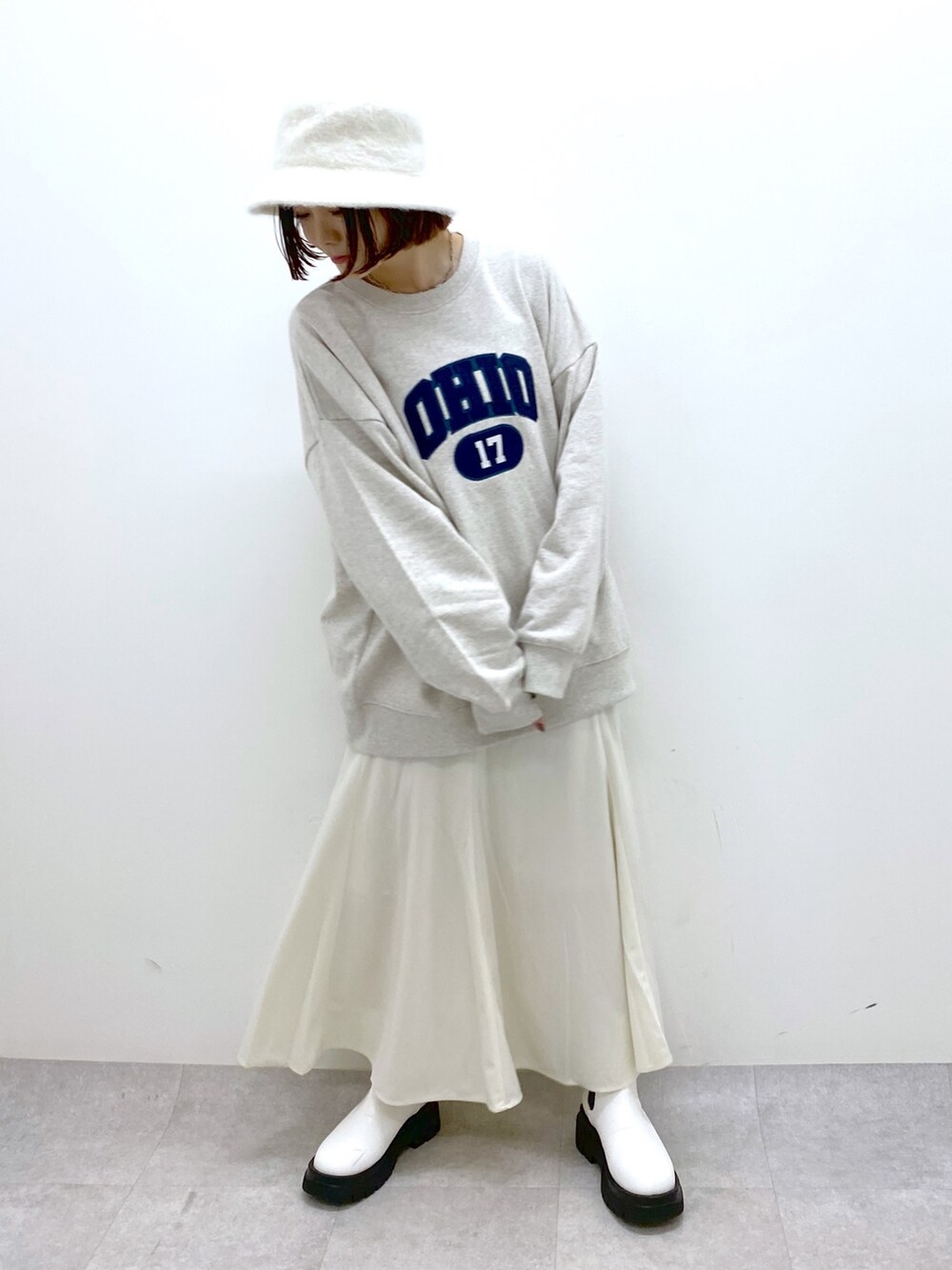 ベージュ系のトップス、ホワイト系のスカート、ホワイト系のシューズを着用したレディースの秋コーディネートの2枚目の写真