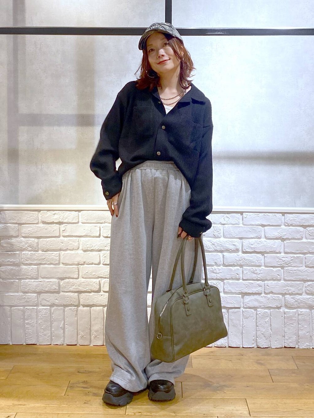 ブラック系のスニーカー、グリーン系のボストンバッグ、グレー系のスウェットパンツを着用したレディースの秋コーディネートの4枚目の写真