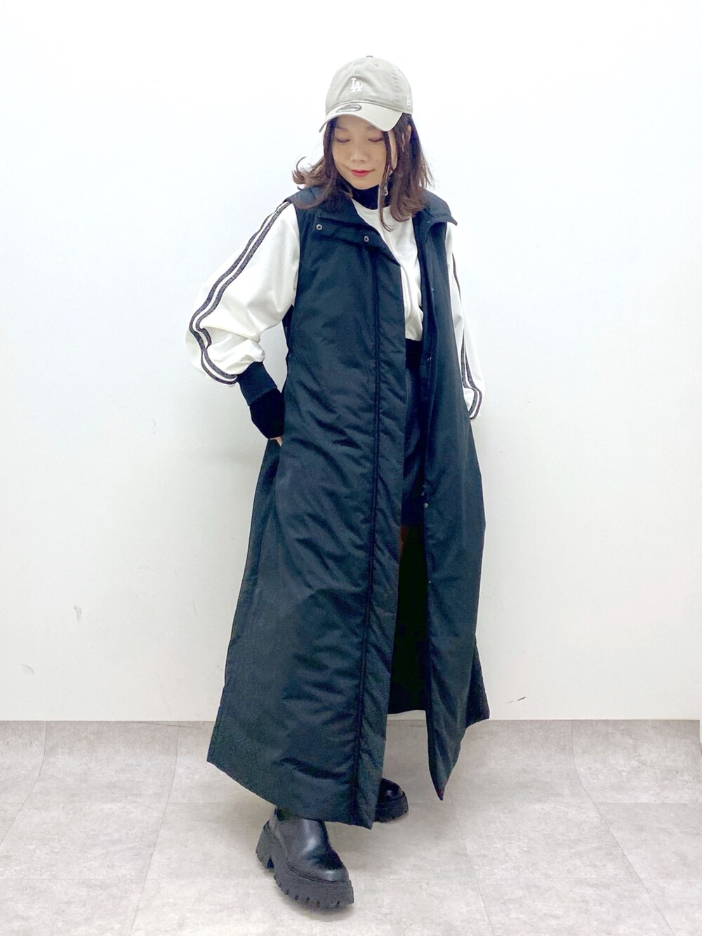 ブラック系のベスト、ブラック系のブーツ、ホワイト系のジャージを着用したレディースの秋コーディネートの9枚目の写真