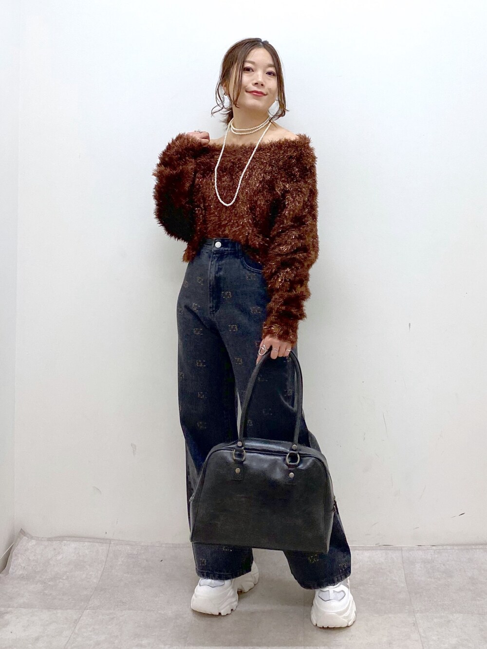 ブラウン系のニット/セーター、ブラック系のボストンバッグ、ホワイト系のスニーカーを着用したレディースの冬コーディネートの5枚目の写真