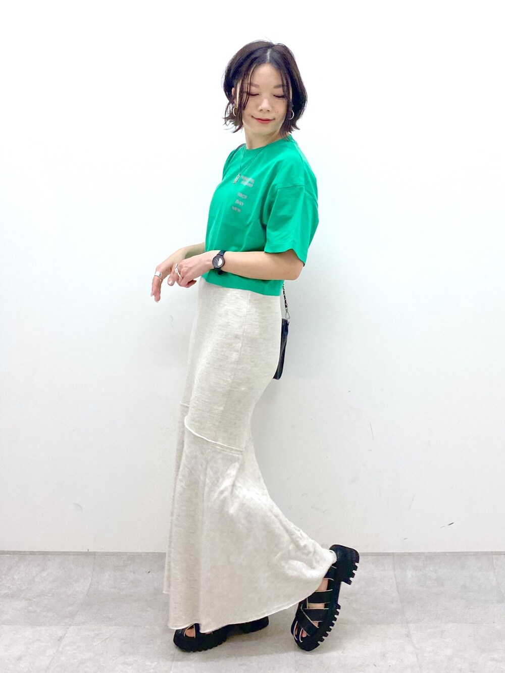 ブラック系のバッグ、ブラック系のサンダル、ベージュ系のスカートを着用したレディースの春コーディネートの3枚目の写真