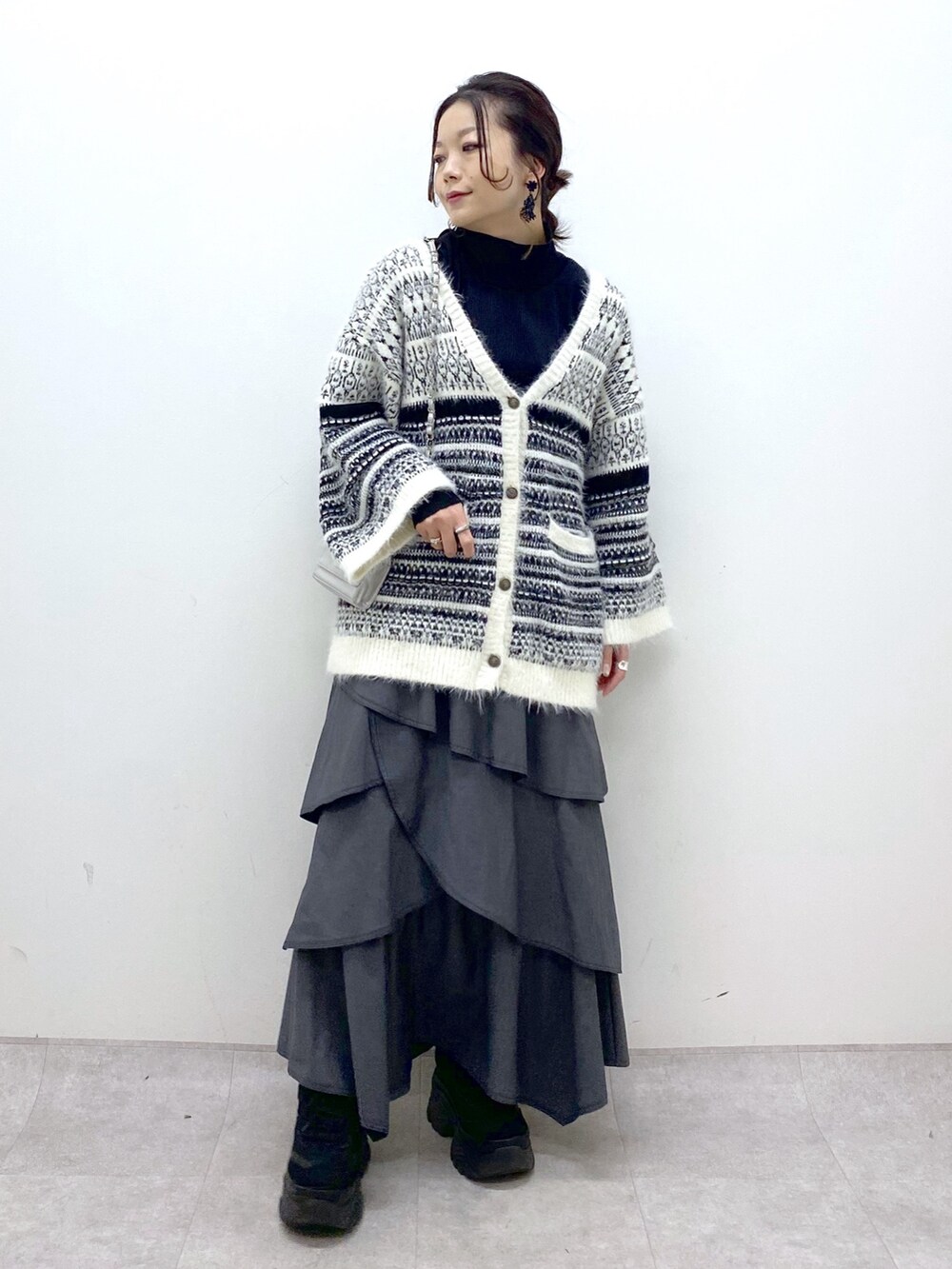 ホワイト系のカーディガン/ボレロ、グレー系のスカート、ブラック系のスニーカーを着用したレディースの冬コーディネートの2枚目の写真