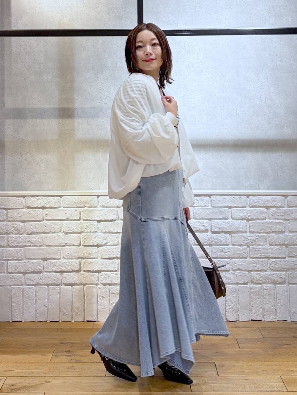 ブラウン系のハンドバッグ、ホワイト系のニット/セーター、ブラック系のサンダルを着用したレディースの春コーディネートの7枚目の写真