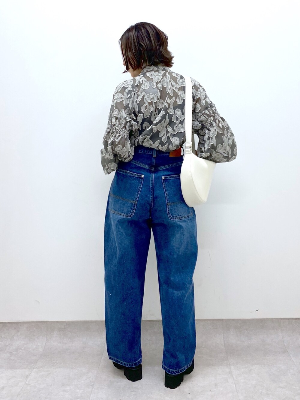 ブルー系のパンツ、グレー系のトップス、ホワイト系のショルダーバッグを着用したレディースの春コーディネートの3枚目の写真