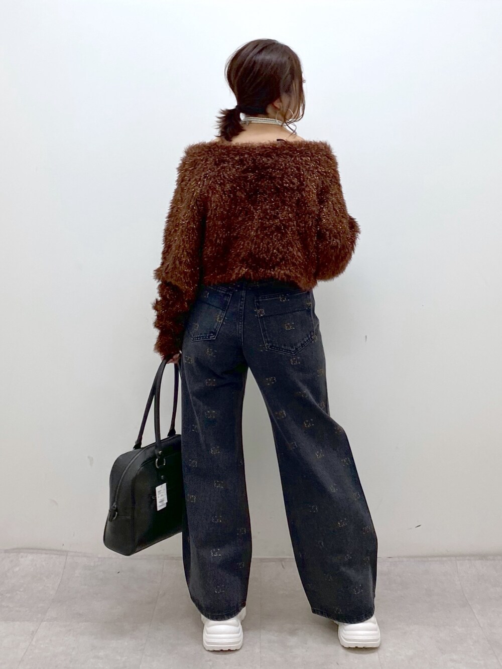 ブラウン系のニット/セーター、ブラック系のボストンバッグ、ホワイト系のスニーカーを着用したレディースの冬コーディネートの7枚目の写真