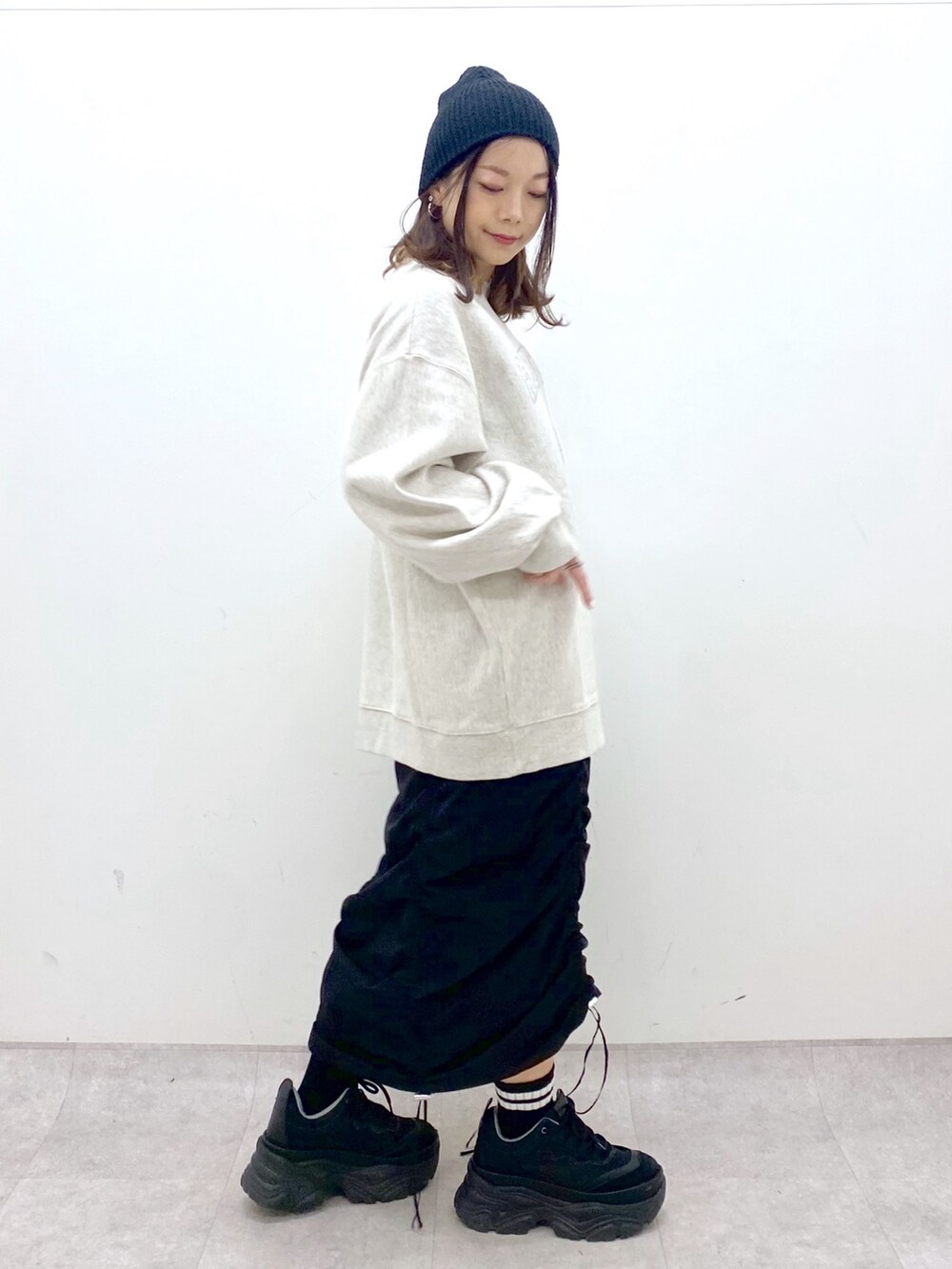 ベージュ系のスウェット、ブラック系のワンピース、ブラック系のスニーカーを着用したレディースの冬コーディネートの5枚目の写真