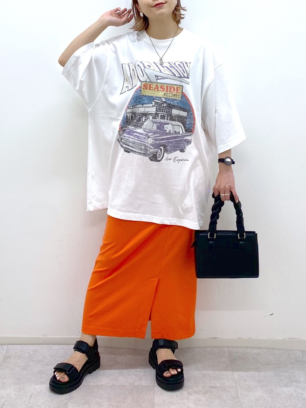 ホワイト系のTシャツ/カットソー、オレンジ系のスカート、ブラック系のショルダーバッグを着用したレディースの夏コーディネートの4枚目の写真