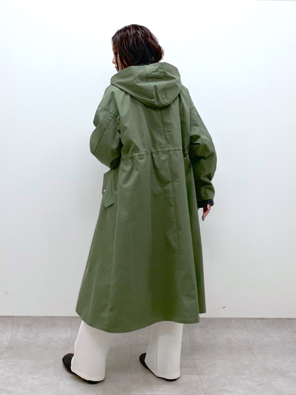 グリーン系のモッズコート、ホワイト系のスラックス、ブラック系のシューズを着用したレディースの冬コーディネートの4枚目の写真