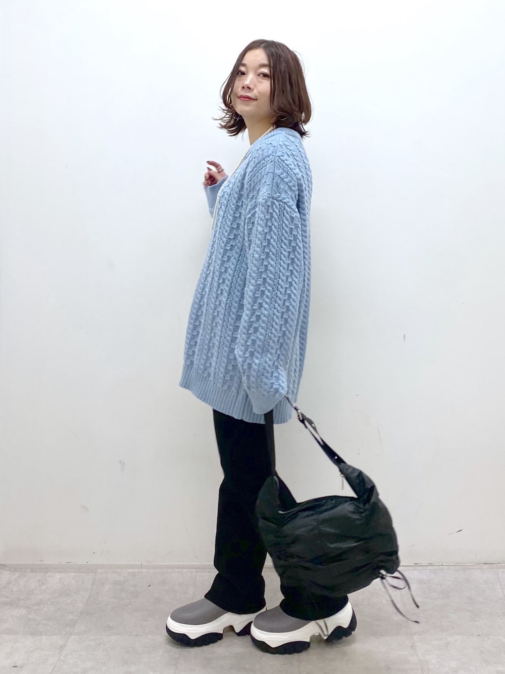 グリーン系のニット/セーター、ブラック系のショルダーバッグ、ブラック系のデニムパンツを着用したレディースの冬コーディネートの4枚目の写真