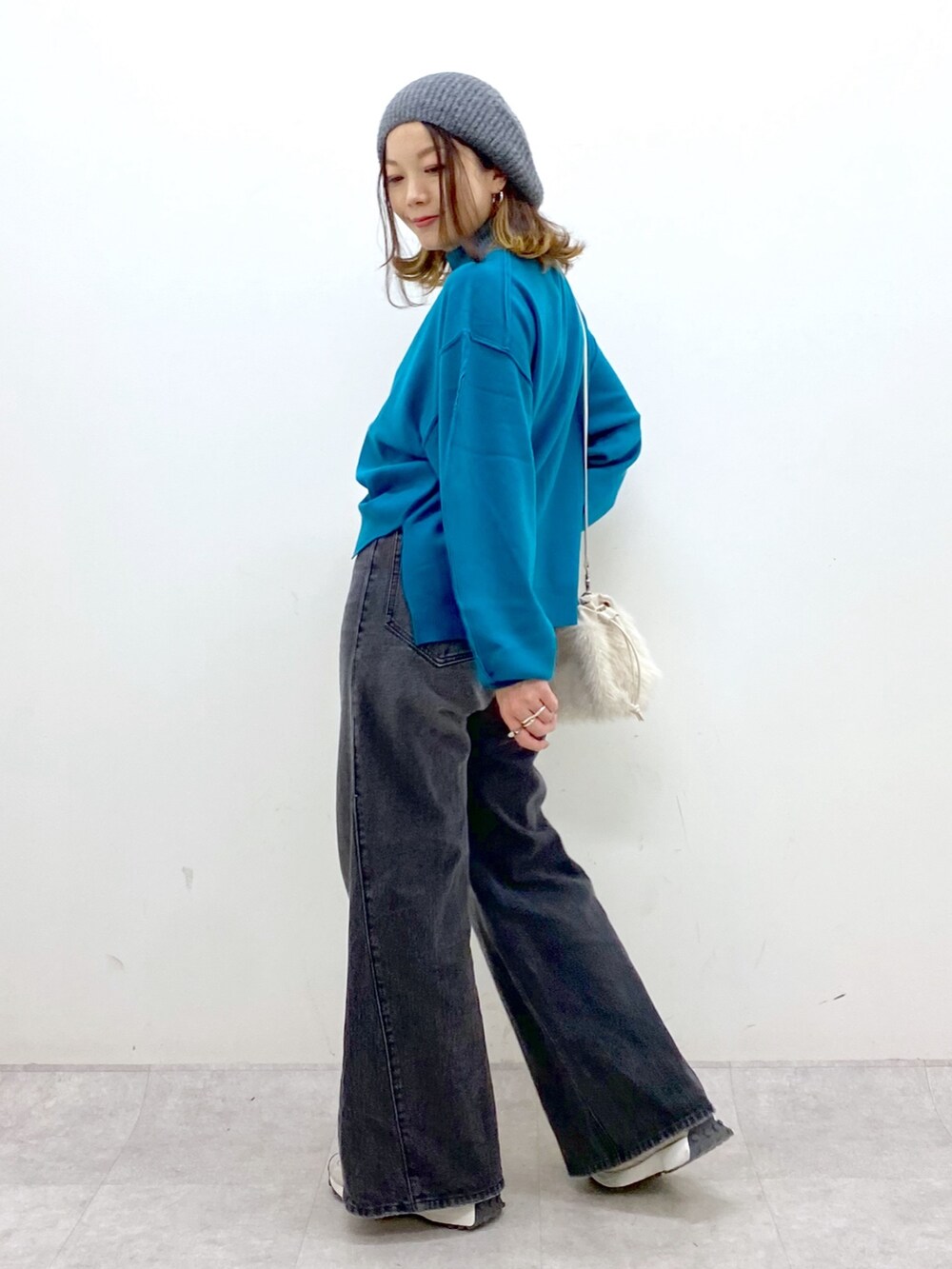 ブラック系のデニムパンツ、ホワイト系のショルダーバッグ、ブルー系のニット/セーターを着用したレディースの秋コーディネートの3枚目の写真