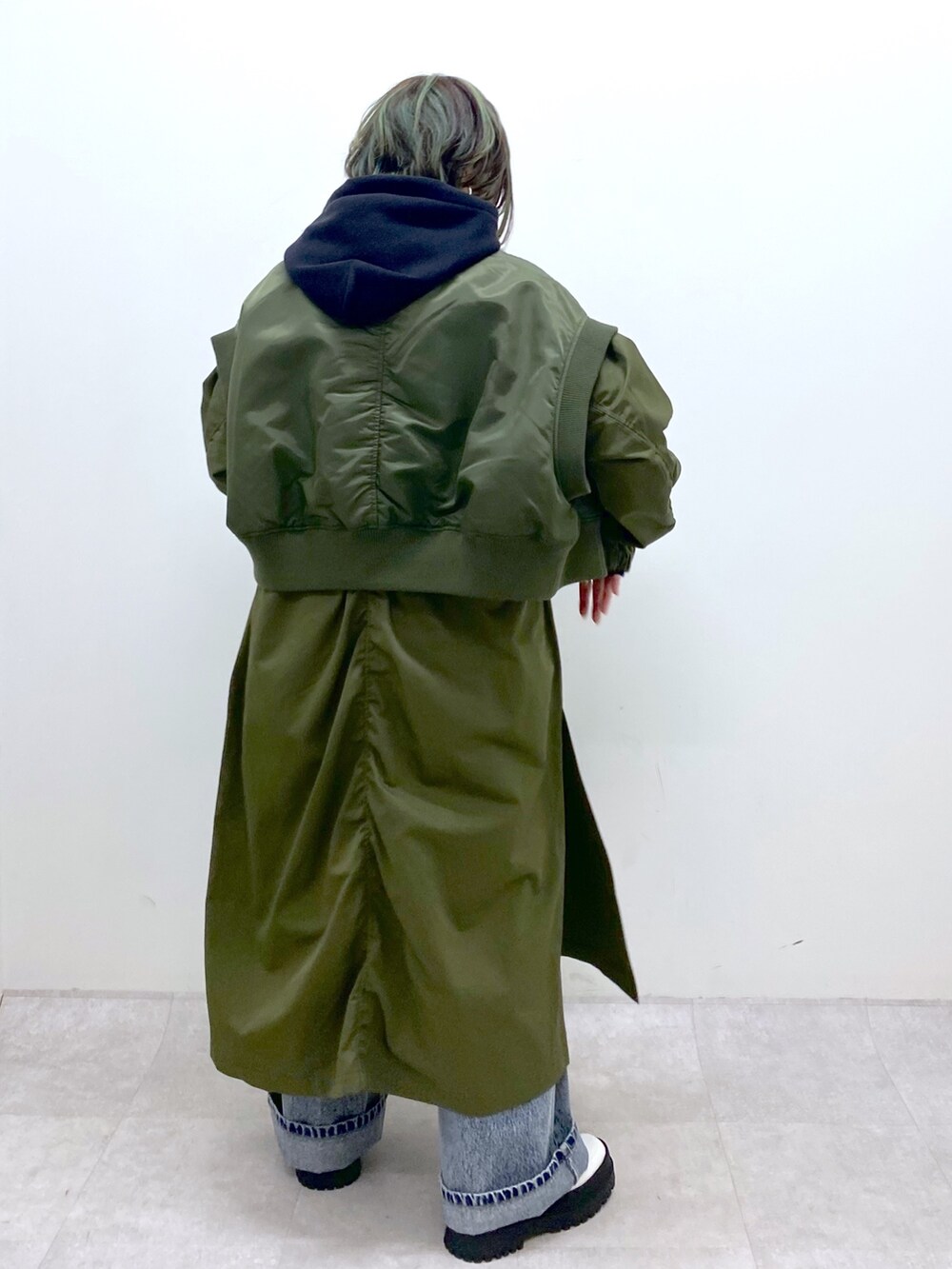 グリーン系のモッズコート、ブラック系のトップス、ブルー系のデニムパンツを着用したレディースの冬コーディネートの5枚目の写真