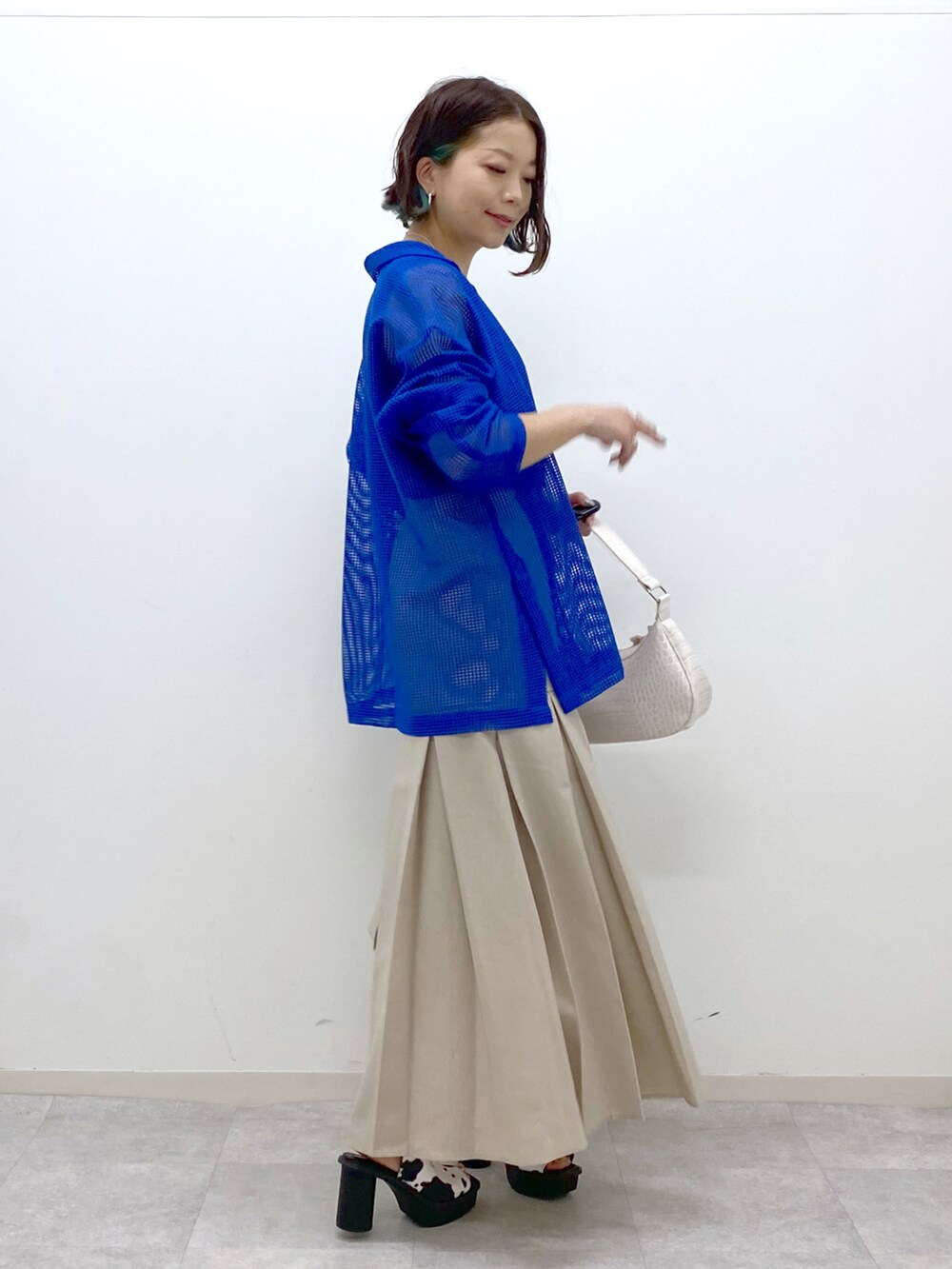 ブルー系のテーラードジャケット、ブラック系のタンクトップ、ベージュ系のスカートを着用したレディースの春コーディネートの2枚目の写真