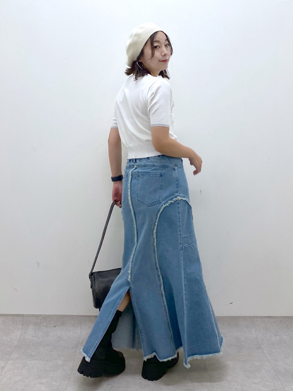 ブルー系のデニムスカート、ホワイト系のニット/セーター、ブラック系のショルダーバッグを着用したレディースの夏コーディネートの6枚目の写真