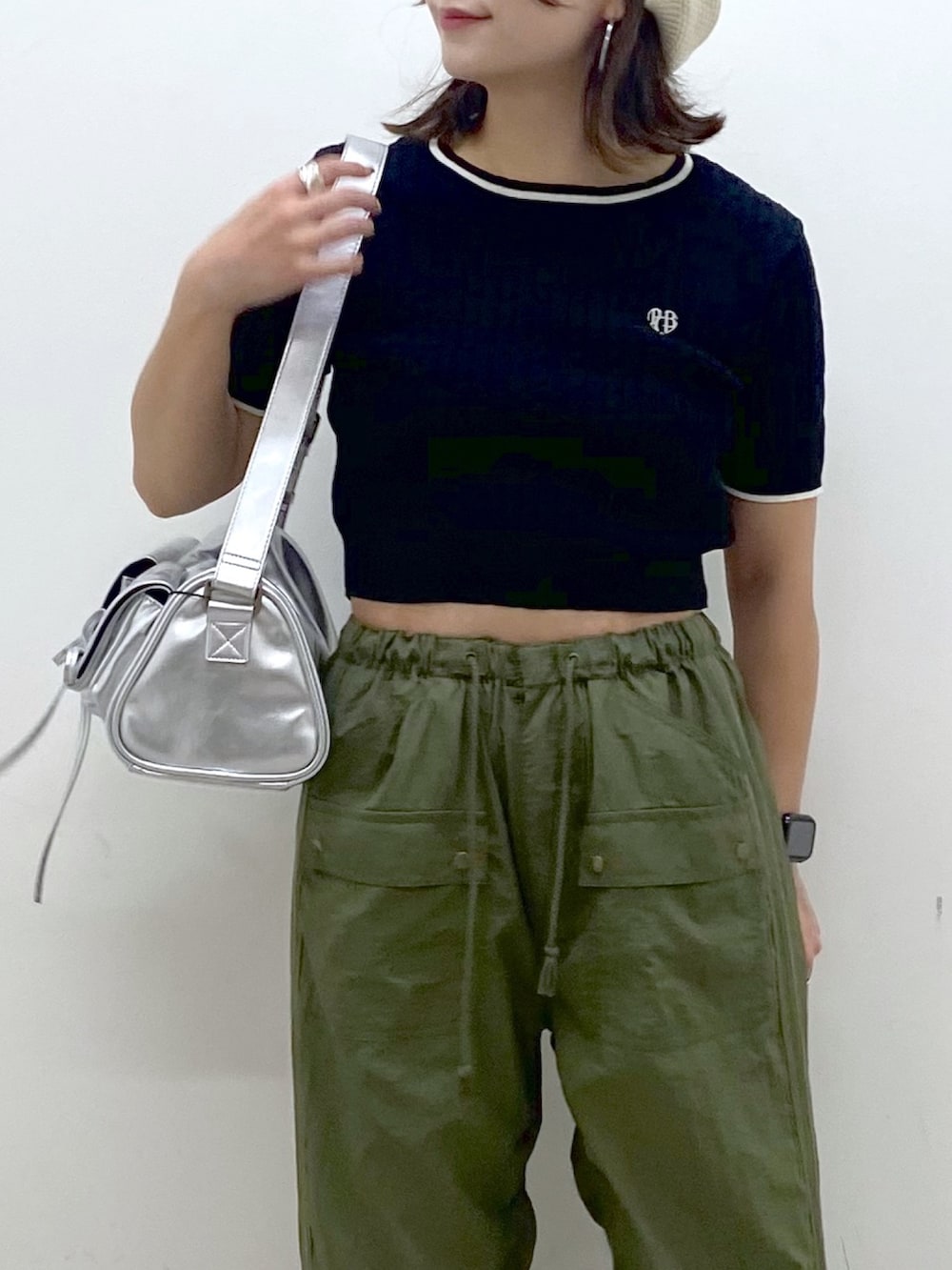 グリーン系のカーゴパンツ、ブラック系のサンダル、シルバー系のショルダーバッグを着用したレディースの夏コーディネートの2枚目の写真