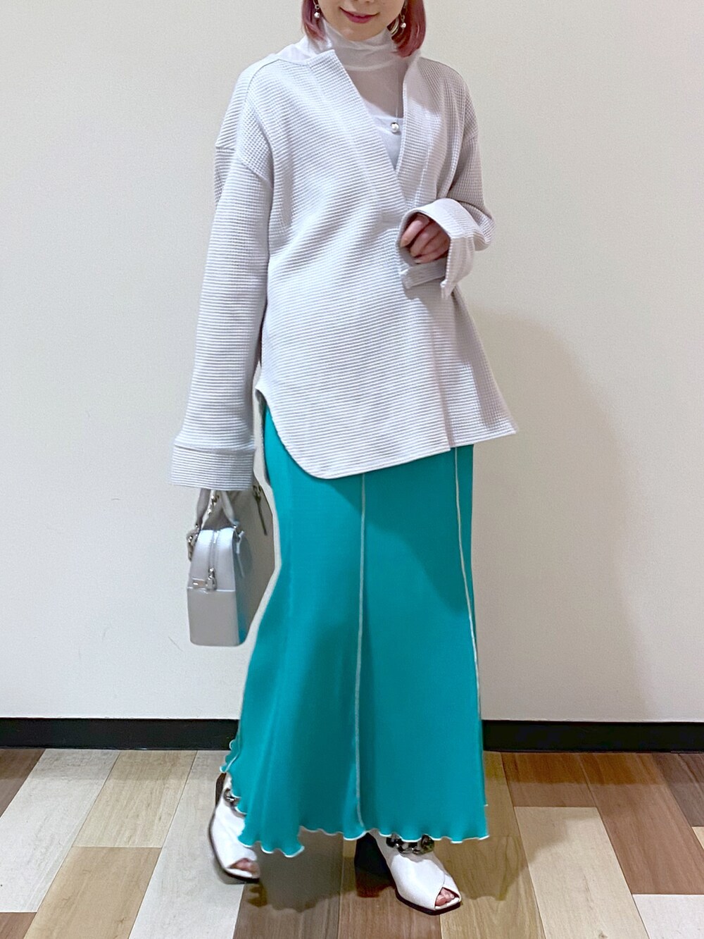 シルバー系のショルダーバッグ、グリーン系のスカート、ホワイト系のパンプスを着用したレディースの冬コーディネートの3枚目の写真