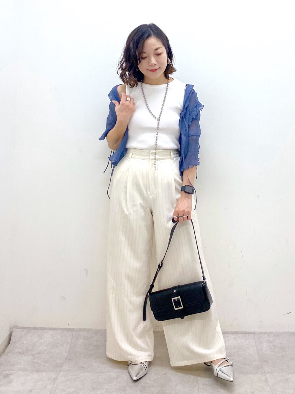 ホワイト系のスラックス、ブラック系のハンドバッグ、シルバー系のパンプスを着用したレディースの夏コーディネートの8枚目の写真