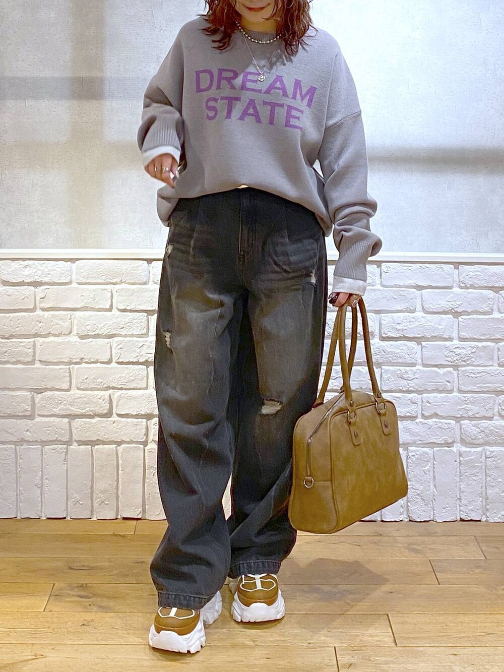 ベージュ系のスニーカー、イエロー系のボストンバッグ、ブラック系のデニムパンツを着用したレディースの秋コーディネートの3枚目の写真