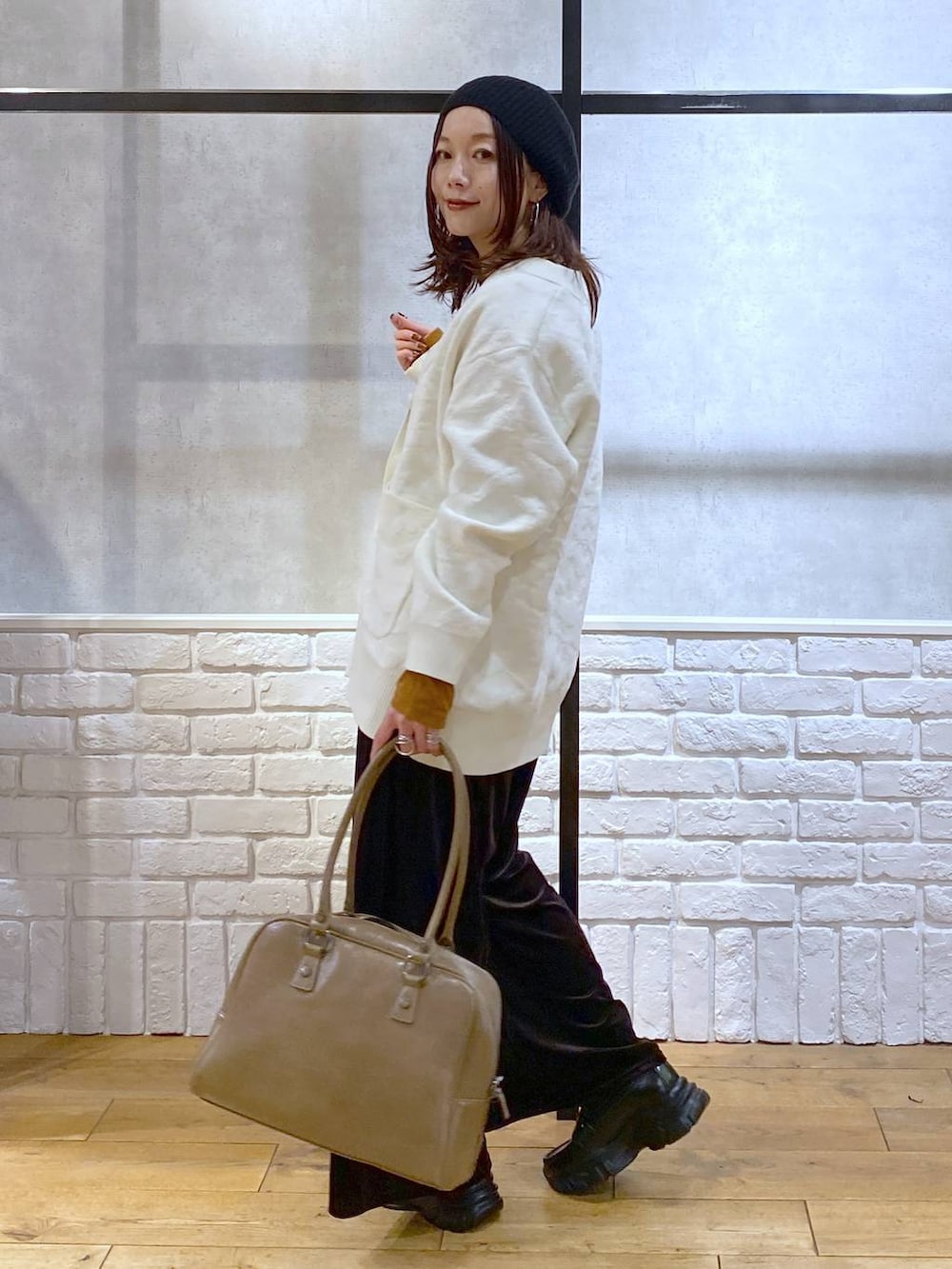 ベージュ系のボストンバッグ、イエロー系のTシャツ/カットソー、ブラック系のローファーを着用したレディースの冬コーディネートの5枚目の写真