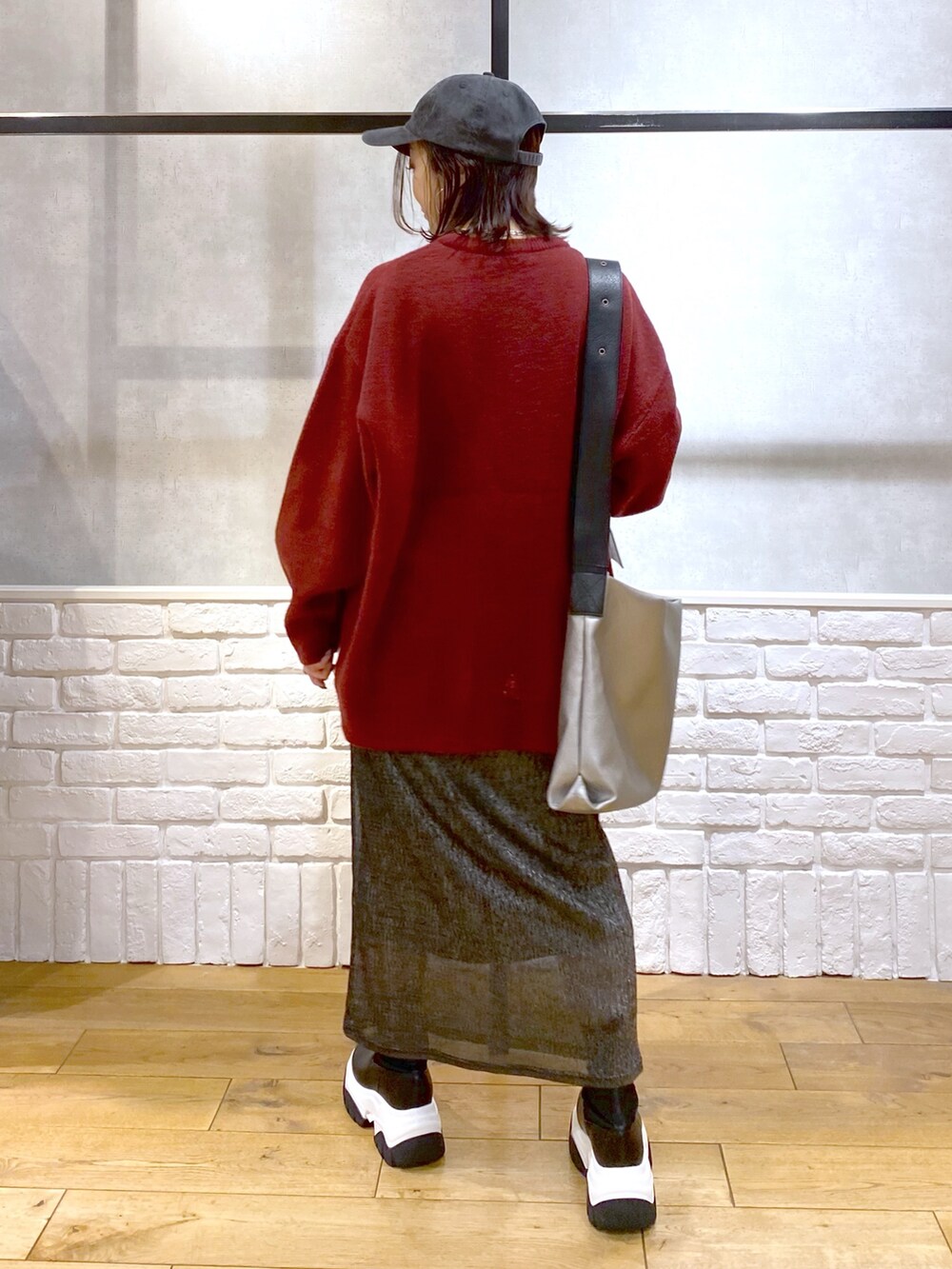 ブラック系のスカート、ブラック系のブーツ、シルバー系のトートバッグを着用したレディースの冬コーディネートの6枚目の写真