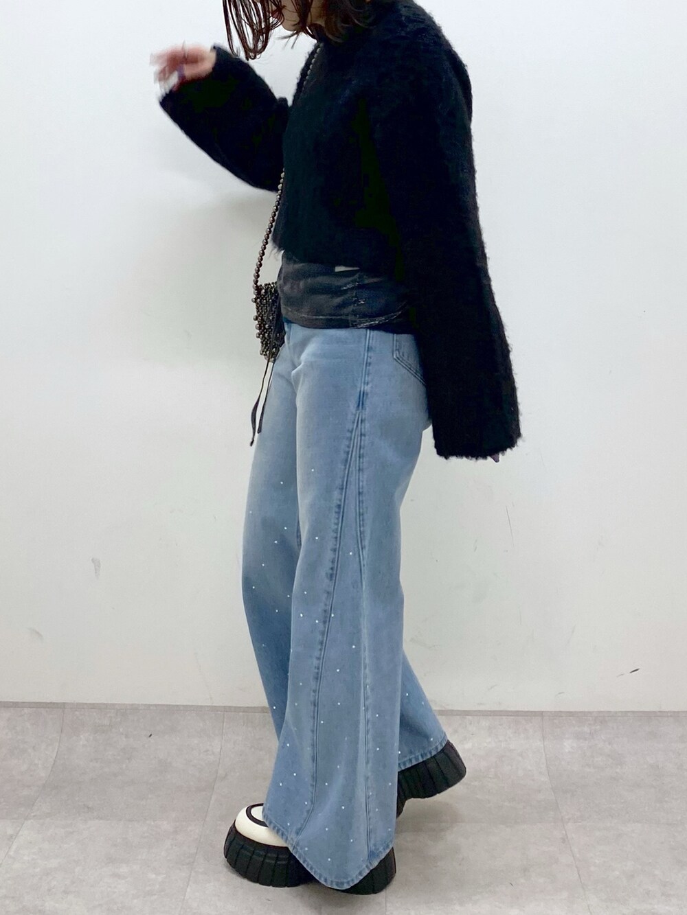 ブラック系のニット/セーター、ブルー系のデニムパンツ、ホワイト系のローファーを着用したレディースの冬コーディネートの7枚目の写真