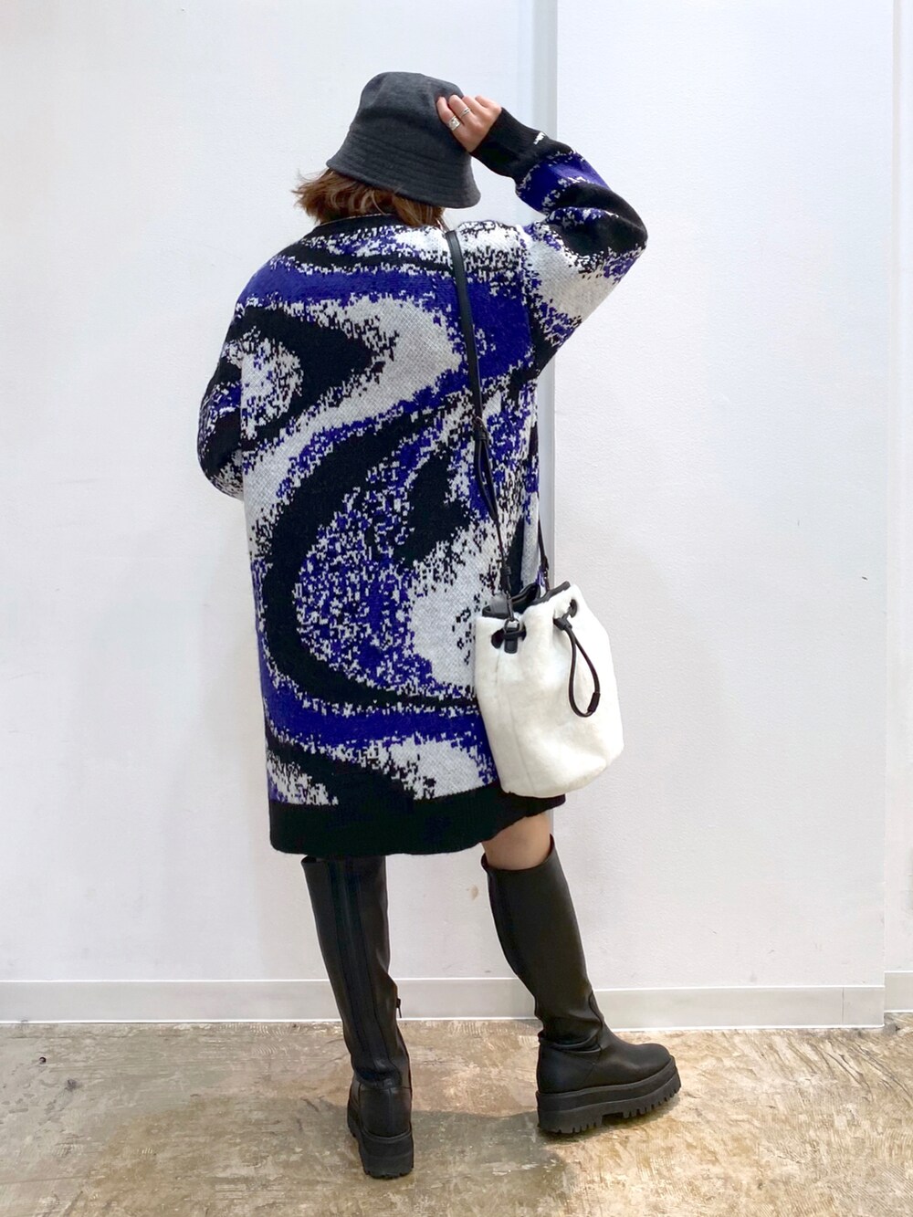 ブラック系のワンピース、ホワイト系のショルダーバッグ、ブラック系のブーツを着用したレディースの冬コーディネートの3枚目の写真