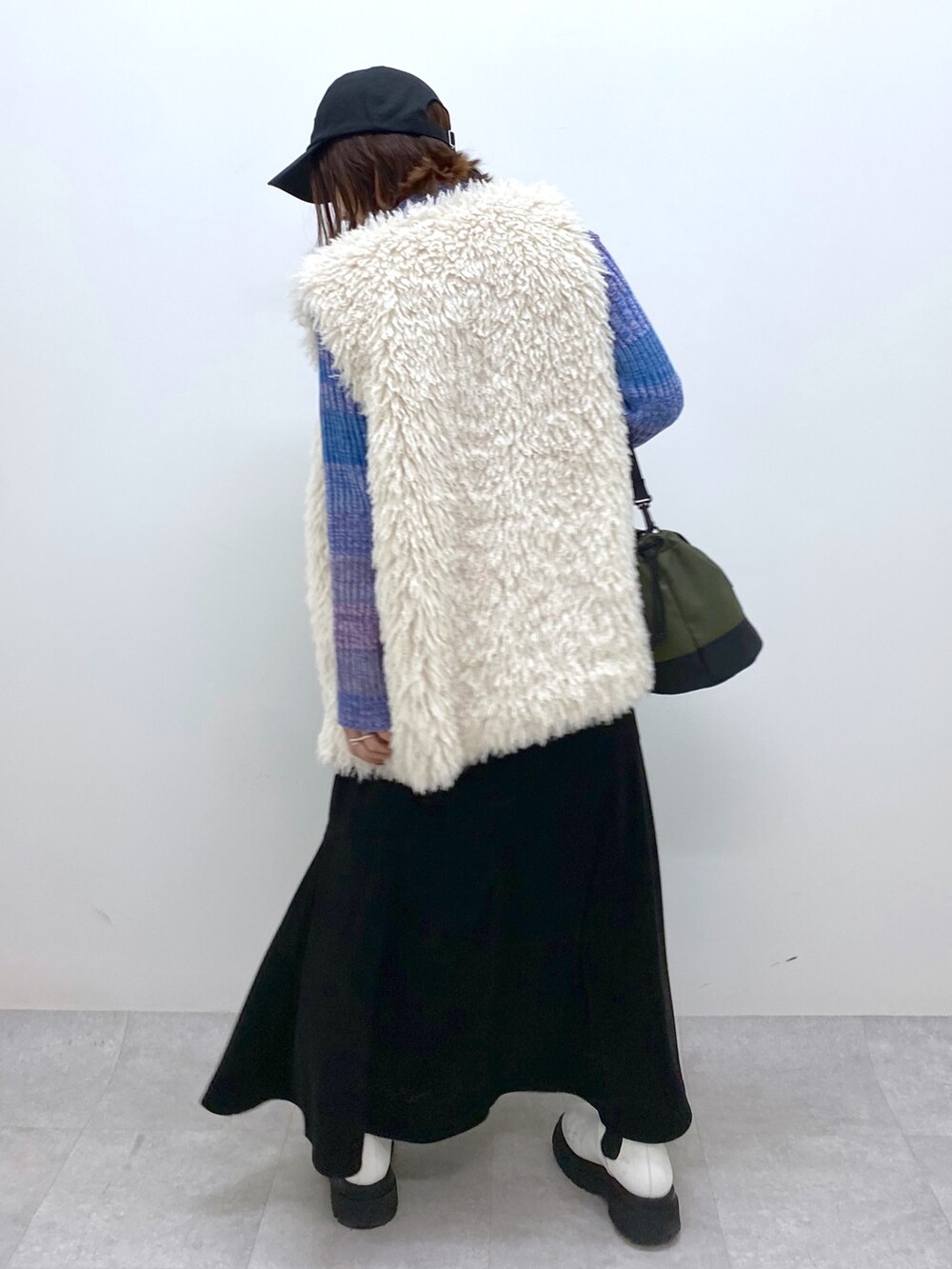 ブラック系のスカート、ホワイト系のシューズ、ブルー系のトップスを着用したレディースの秋コーディネートの4枚目の写真