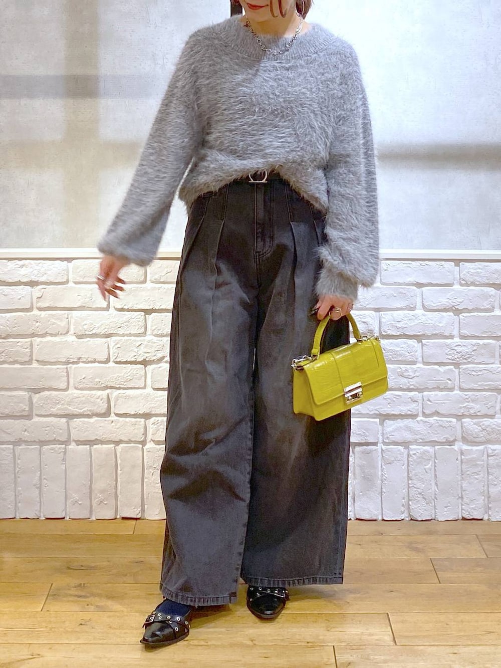 ブラック系のデニムパンツ、イエロー系のハンドバッグ、ブラック系のパンプスを着用したレディースの秋コーディネートの3枚目の写真