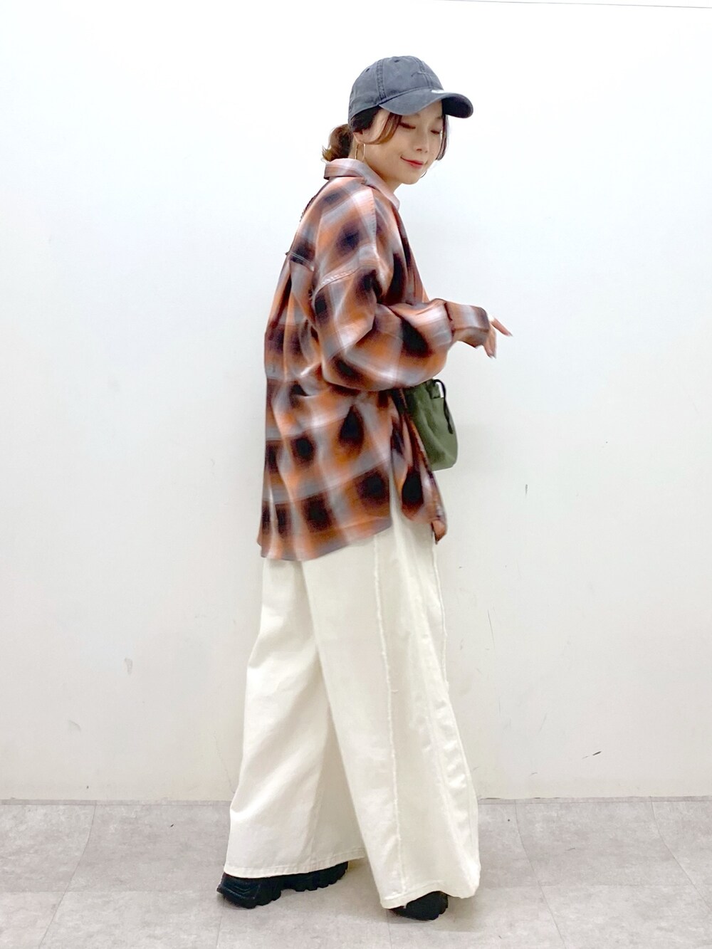 ホワイト系のデニムパンツ、ブラック系のスニーカー、グリーン系のショルダーバッグを着用したレディースの夏コーディネートの7枚目の写真