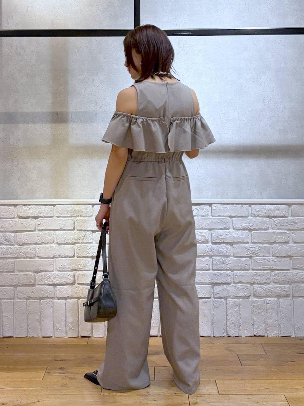 ブラック系のハンドバッグ、ブラック系のサンダル、ベージュ系のサロペット/オーバーオールを着用したレディースの春コーディネートの4枚目の写真