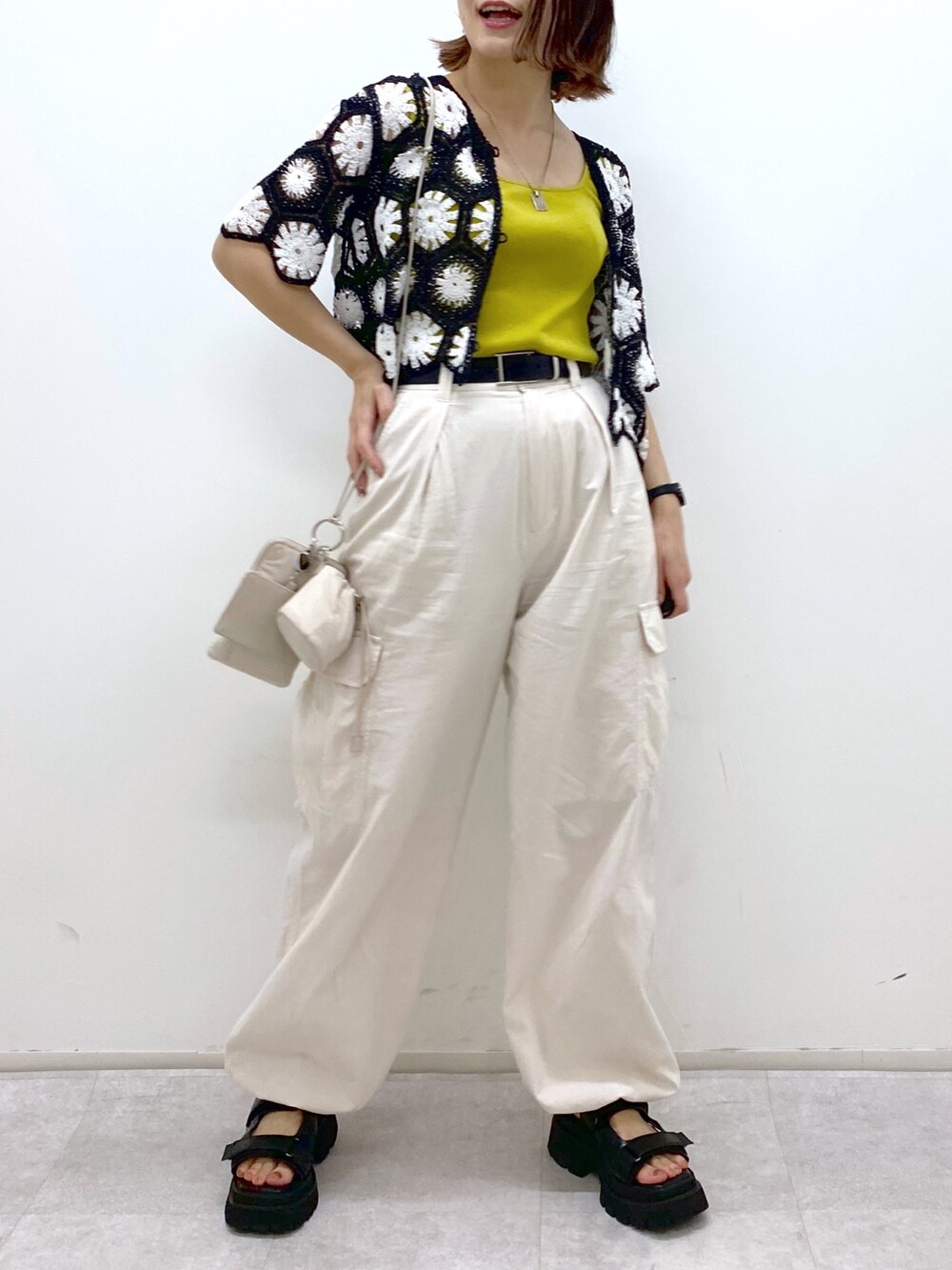 ホワイト系のカーゴパンツ、イエロー系のタンクトップ、ブラック系のトップスを着用したレディースの夏コーディネートの5枚目の写真