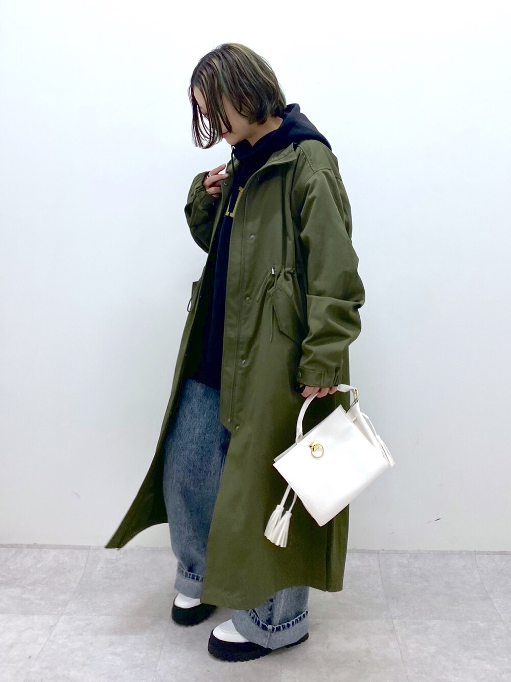 グリーン系のモッズコート、ブラック系のトップス、ブルー系のデニムパンツを着用したレディースの冬コーディネートの4枚目の写真