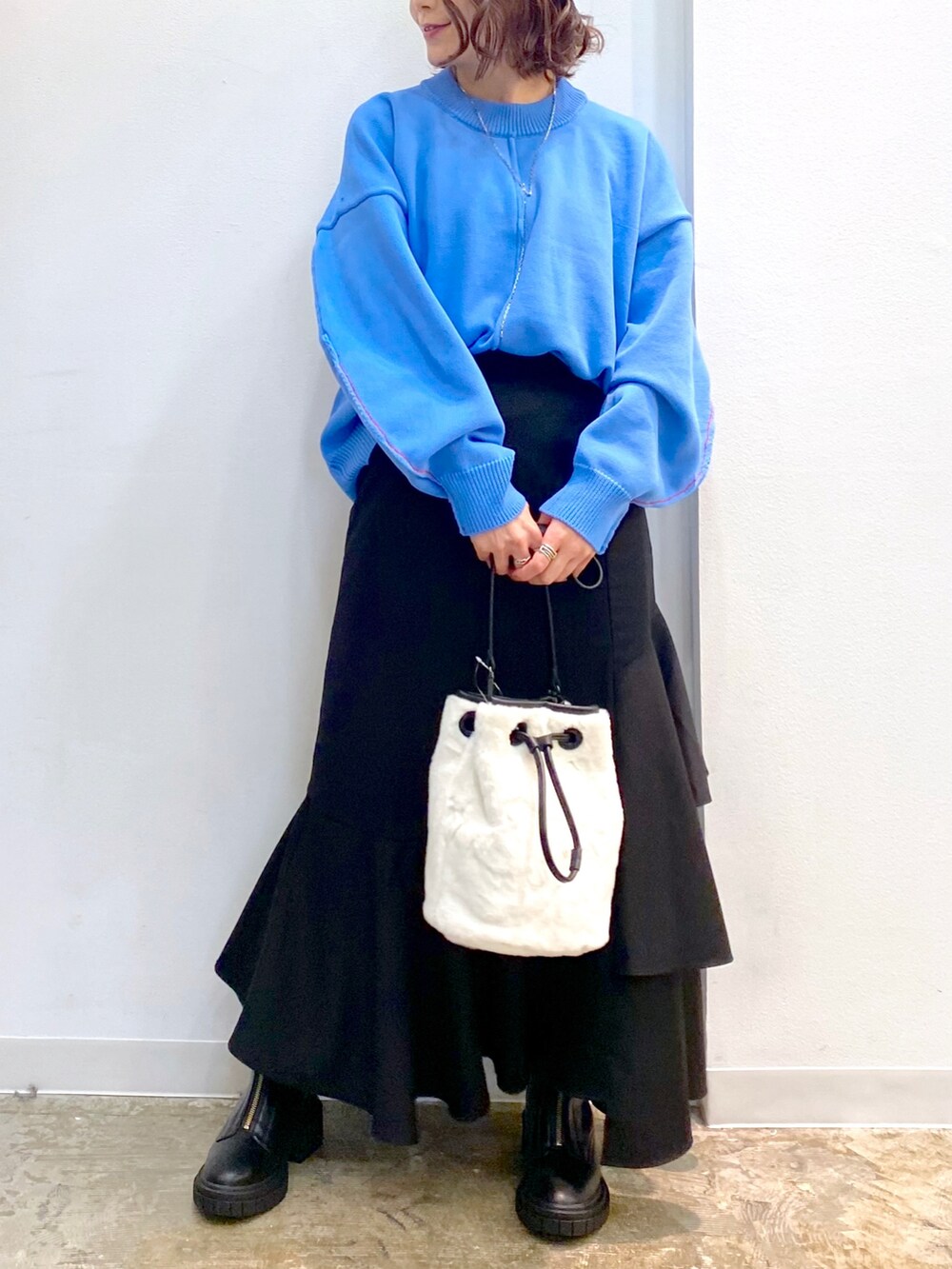 ホワイト系のショルダーバッグ、ブルー系のニット/セーター、ブラック系のスカートを着用したレディースの秋コーディネートの3枚目の写真