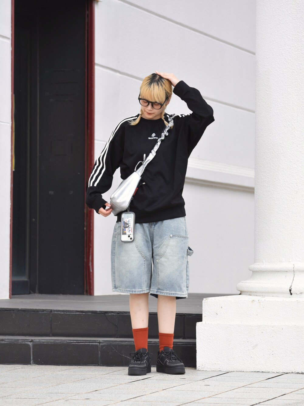 ブラック系のスニーカー、シルバー系のハンドバッグ、ブルー系のデニムパンツを着用したレディースの秋コーディネートの3枚目の写真