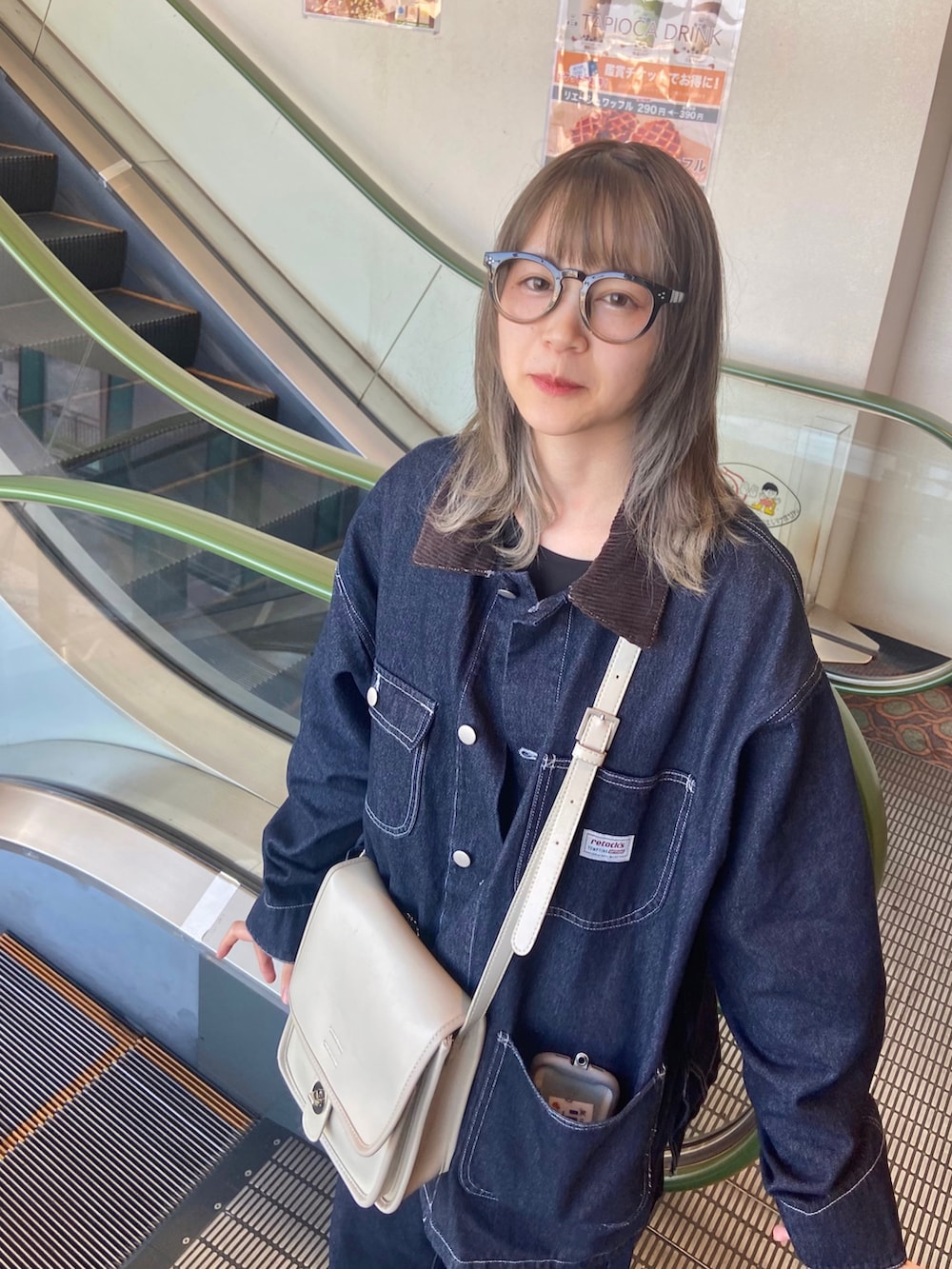 ブルー系のデニムパンツ、ブラック系のブーツ、ブルー系のデニムジャケットを着用したレディースの秋コーディネートの2枚目の写真