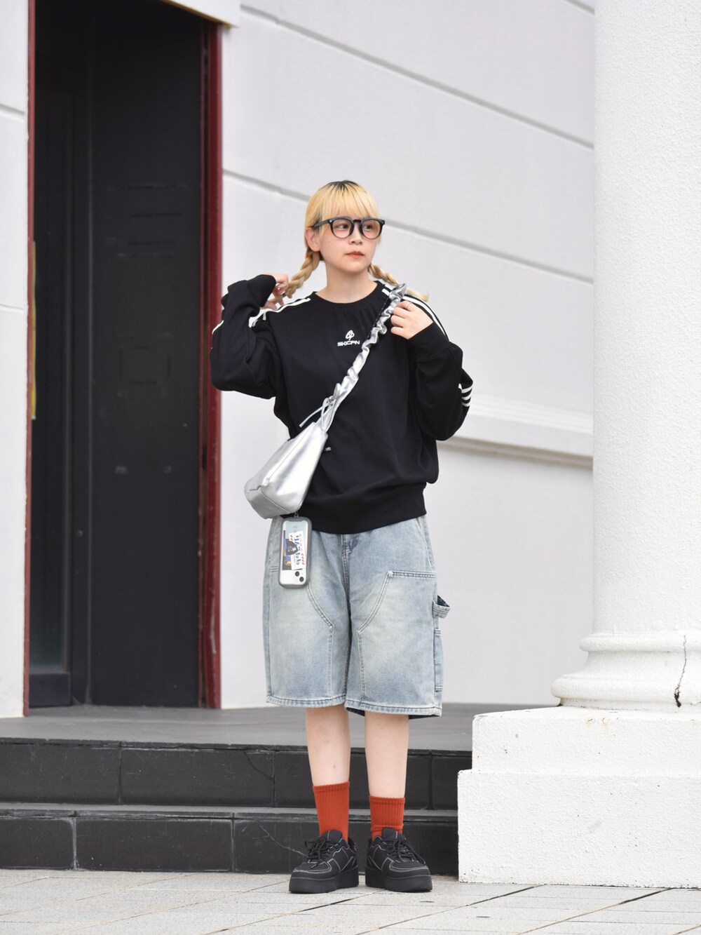 ブラック系のスニーカー、シルバー系のハンドバッグ、ブルー系のデニムパンツを着用したレディースの秋コーディネートの2枚目の写真