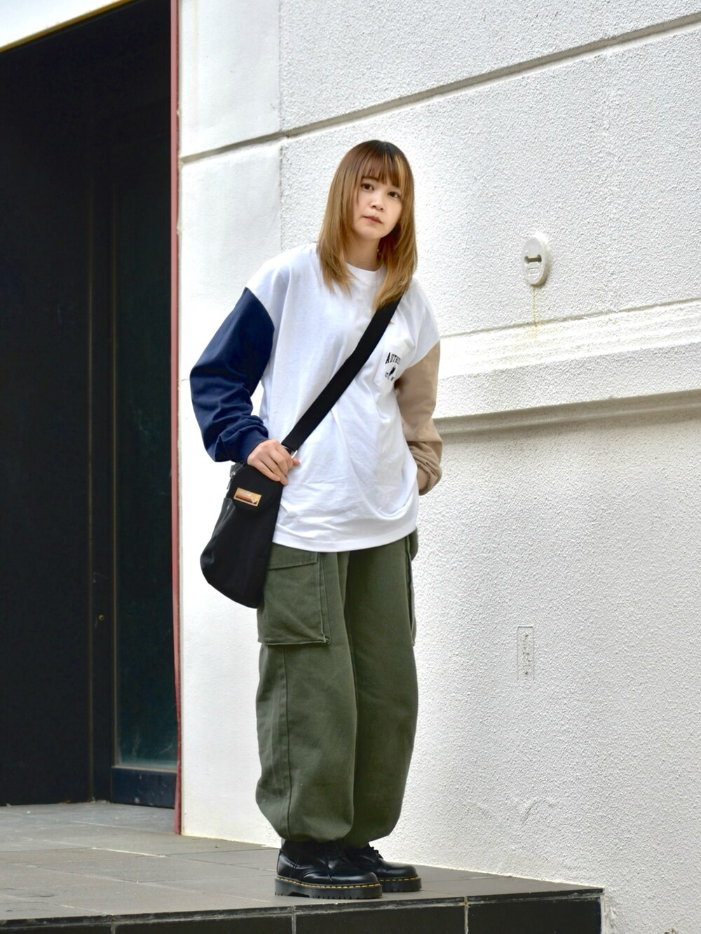 ブラック系のブーツ、グリーン系のカーゴパンツ、ブラック系のショルダーバッグを着用したレディースの春コーディネートの2枚目の写真