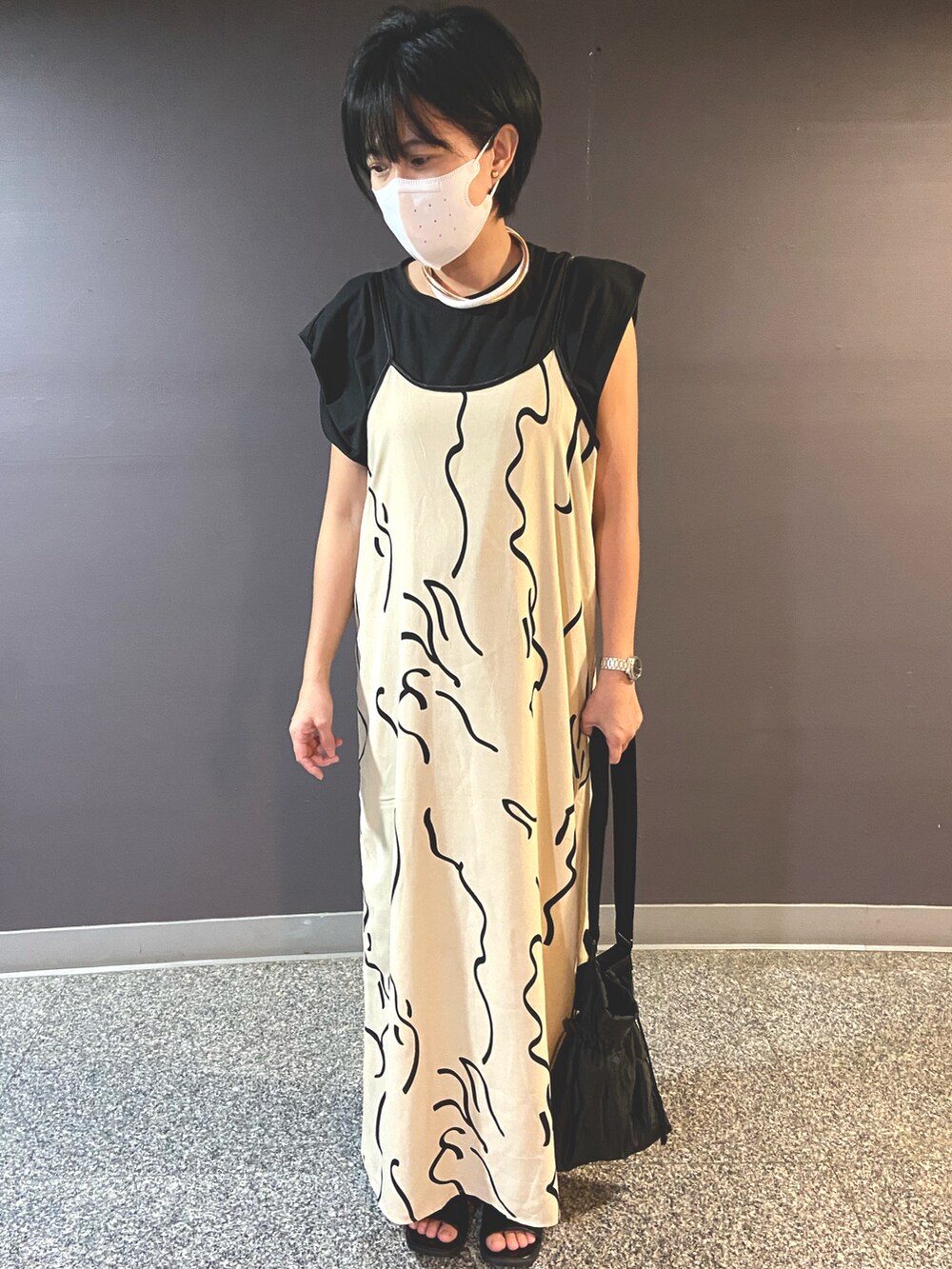 ブラック系のショルダーバッグ、ベージュ系のジャンパースカート、ホワイト系のその他を着用したレディースの夏コーディネートの2枚目の写真