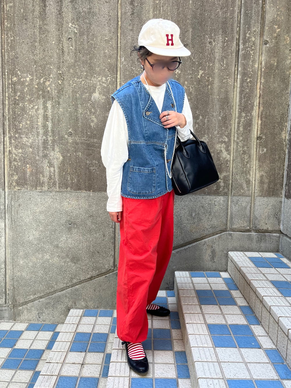 オレンジ系のその他パンツ、ブラック系のバレエシューズ、ブルー系のダウンベストを着用したレディースの春コーディネートの2枚目の写真