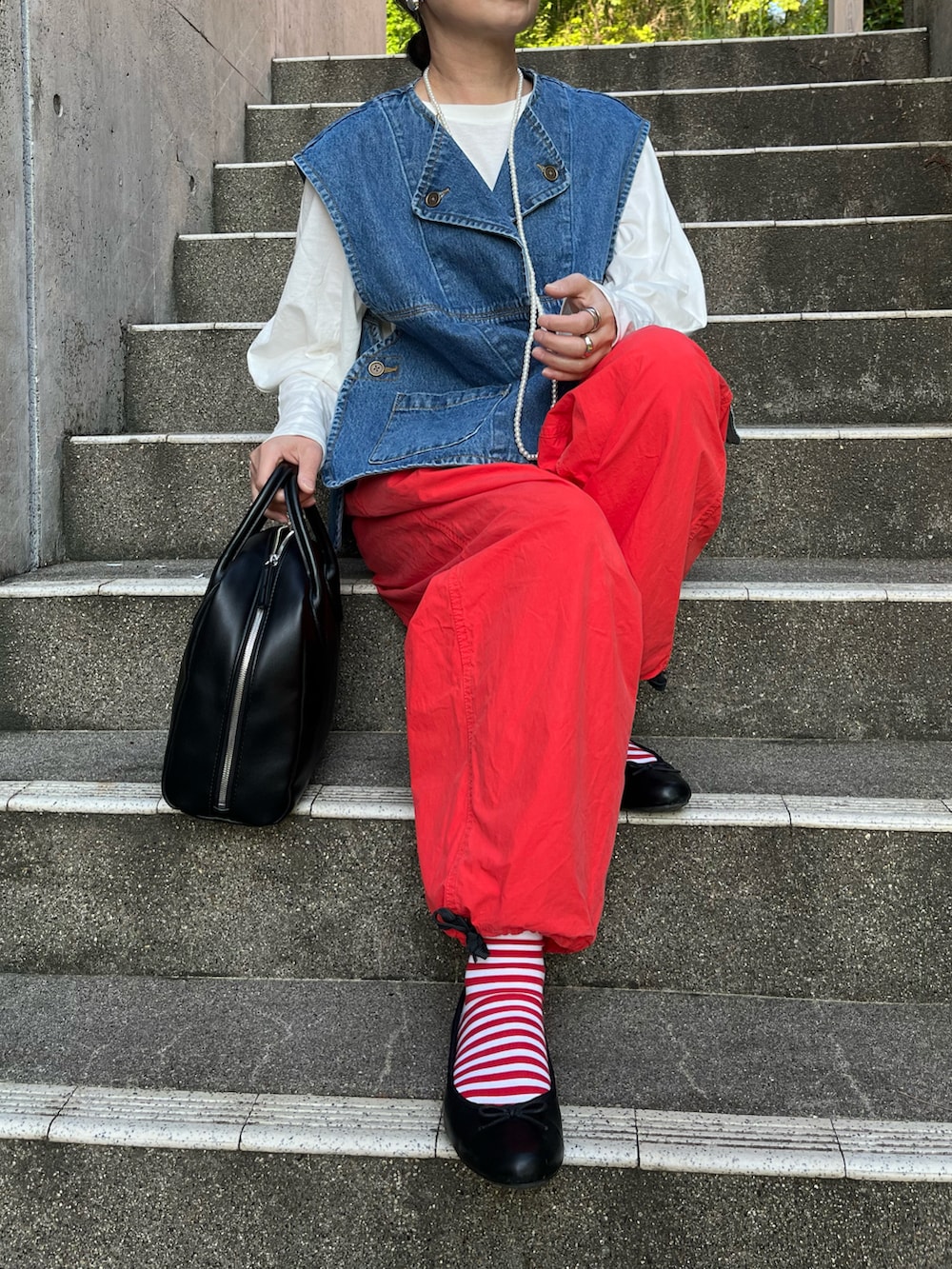 オレンジ系のその他パンツ、ブラック系のバレエシューズ、ブルー系のダウンベストを着用したレディースの春コーディネートの3枚目の写真