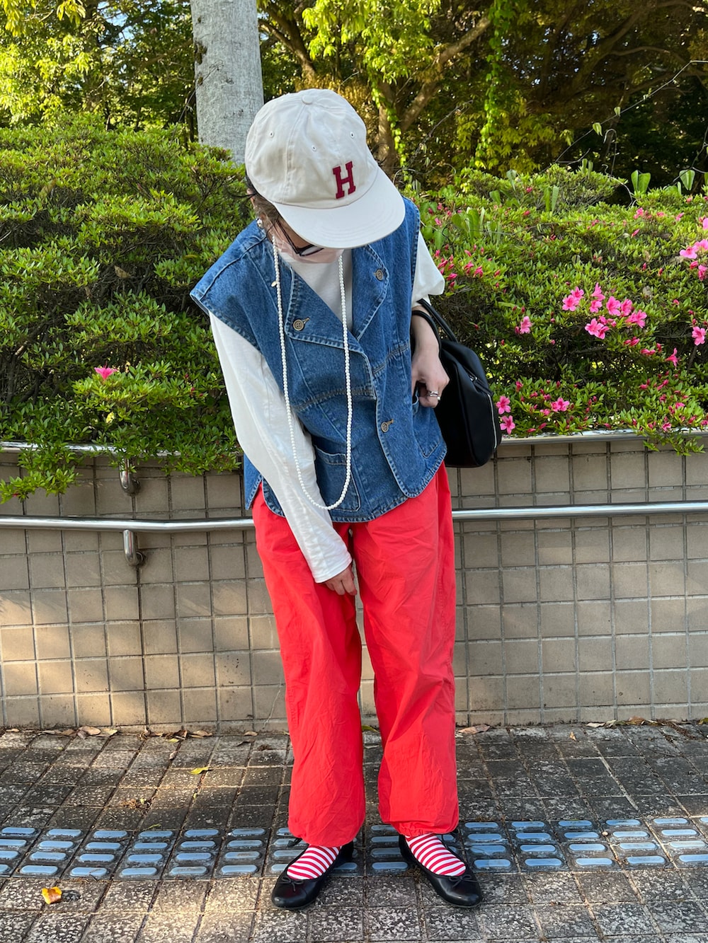 オレンジ系のその他パンツ、ブラック系のバレエシューズ、ブルー系のダウンベストを着用したレディースの春コーディネートの4枚目の写真