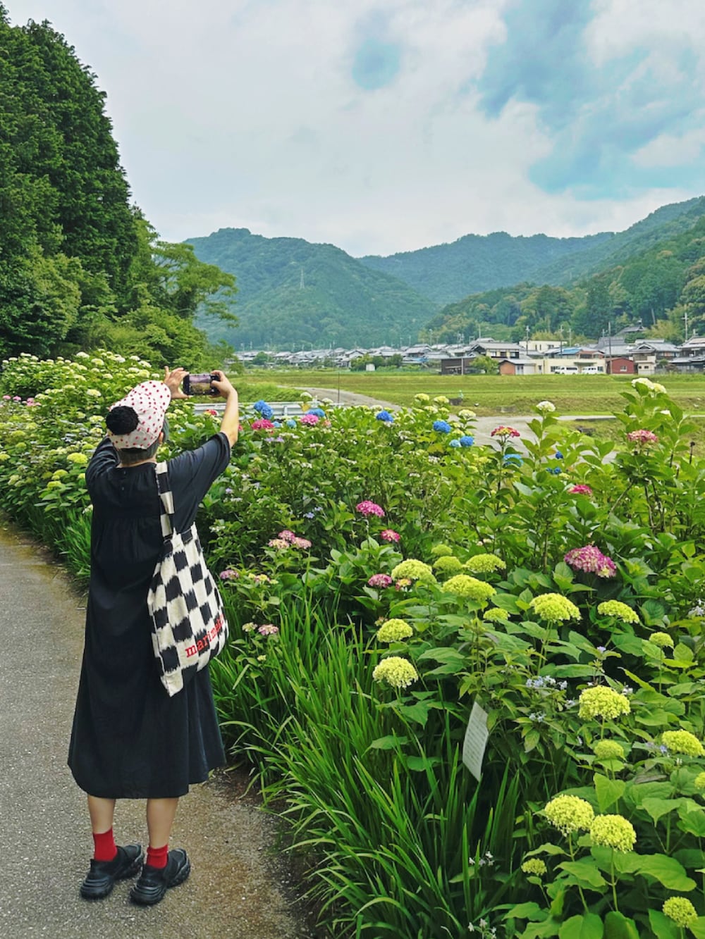 ブラック系のワンピース、ブラック系のトートバッグ、ブラック系のスニーカーを着用したレディースの夏コーディネートの2枚目の写真