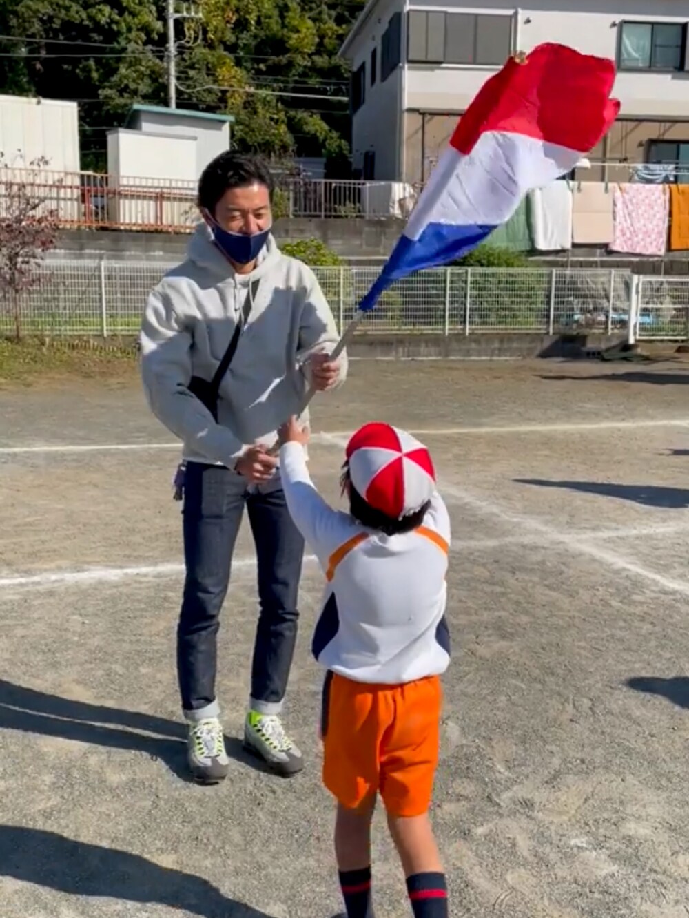 グレー系のスウェット、ブラック系のショルダーバッグ、ブルー系のデニムパンツを着用したメンズの秋コーディネートの2枚目の写真