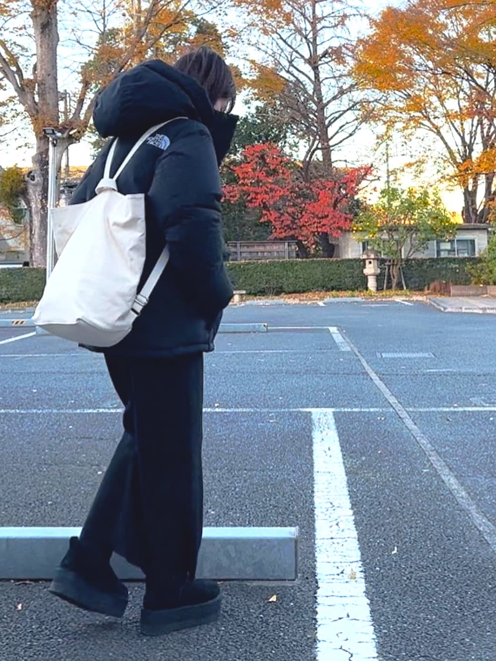 ブラック系のダウンジャケット/コート、ホワイト系のバックパック/リュック、ブラック系のブーツを着用したレディースの冬コーディネートの2枚目の写真