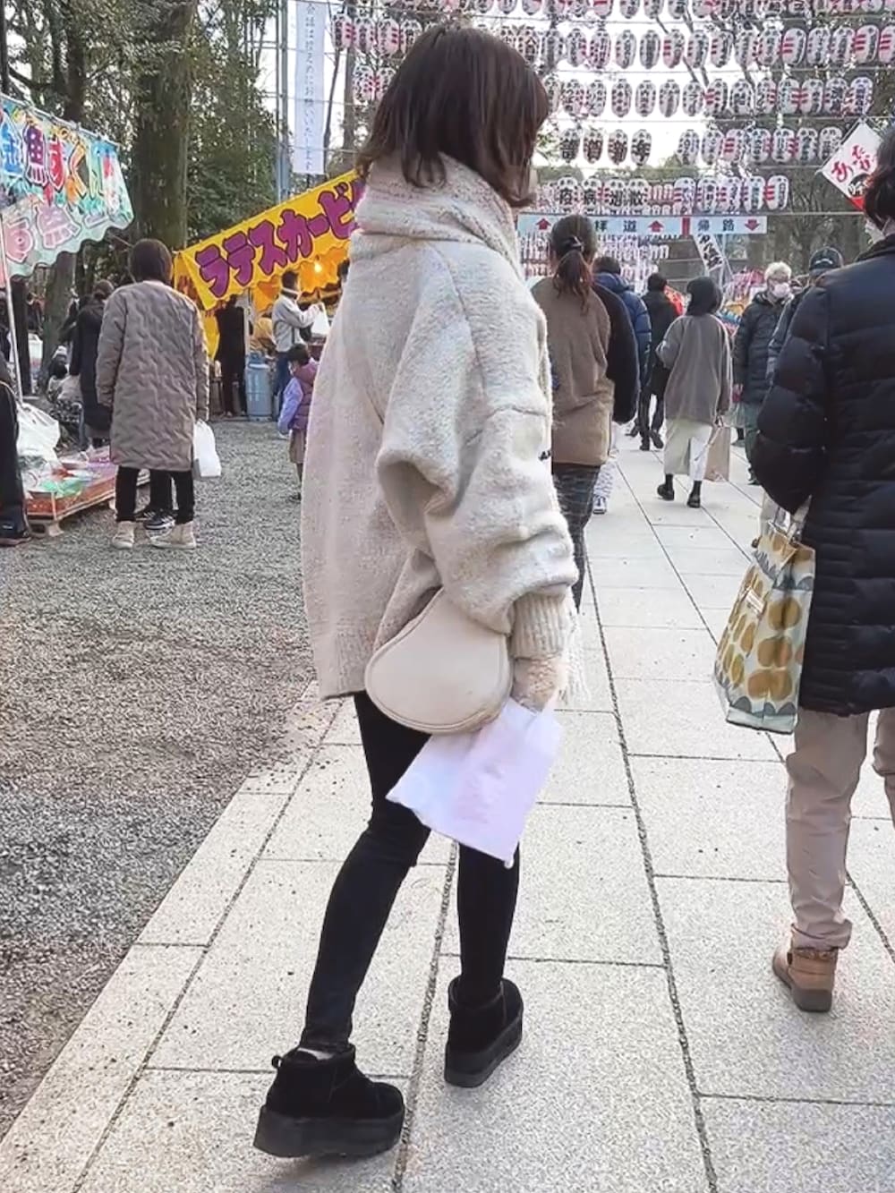 ホワイト系のニット/セーター、ブラック系のデニムパンツ、ブラック系のブーツを着用したレディースの冬コーディネートの2枚目の写真